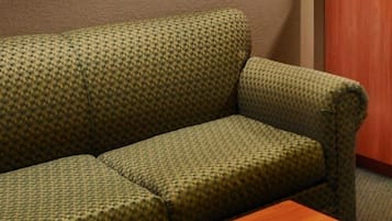 Un canapé à motifs verts, avec une table en bois placée devant.