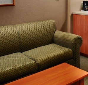 A green patterned sofa with a wooden table in front. - Microtel Inn By Wyndham Parry Sound (Parry Sound)