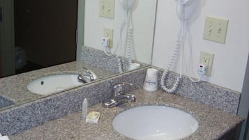 Une salle de bain avec deux lavabos, un miroir, un sèche-cheveux et un distributeur de papier toilette.