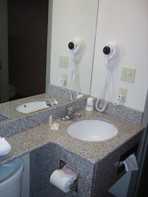 A bathroom with two sinks, a mirror, and two hair dryers mounted on the wall. - Microtel Inn By Wyndham Parry Sound (Parry Sound)