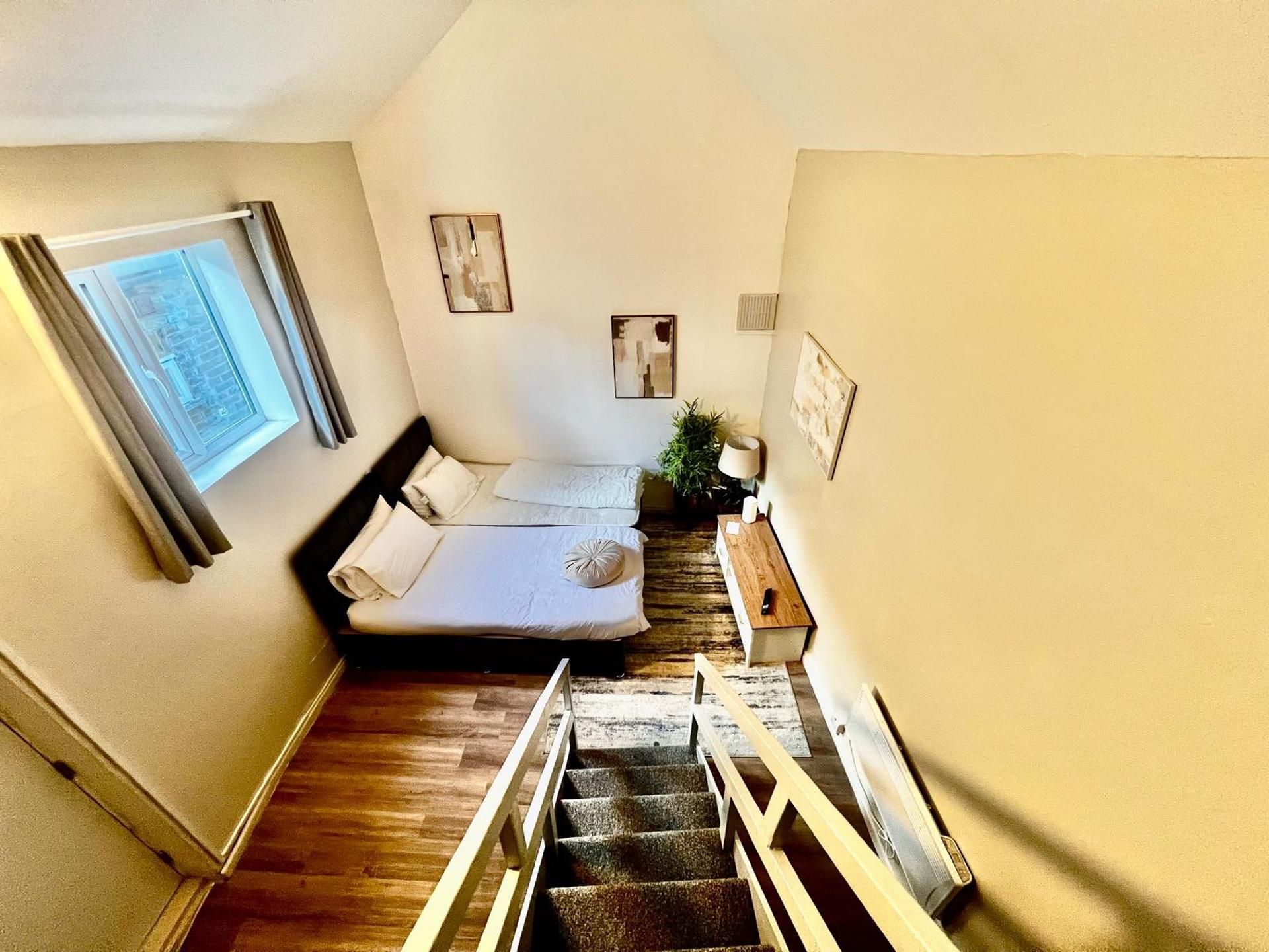 A bedroom with a bed, a window, a staircase, and a plant.