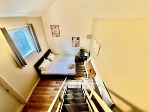 A bedroom with a bed, a window, a staircase, and a plant. - Apartment Sleeps 4 Near Station (Purley)
