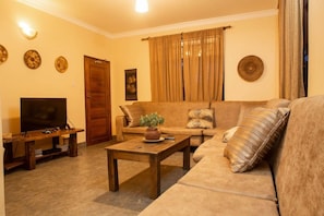 Una sala de estar con sofá, mesa de centro, televisor y decoración mural.
