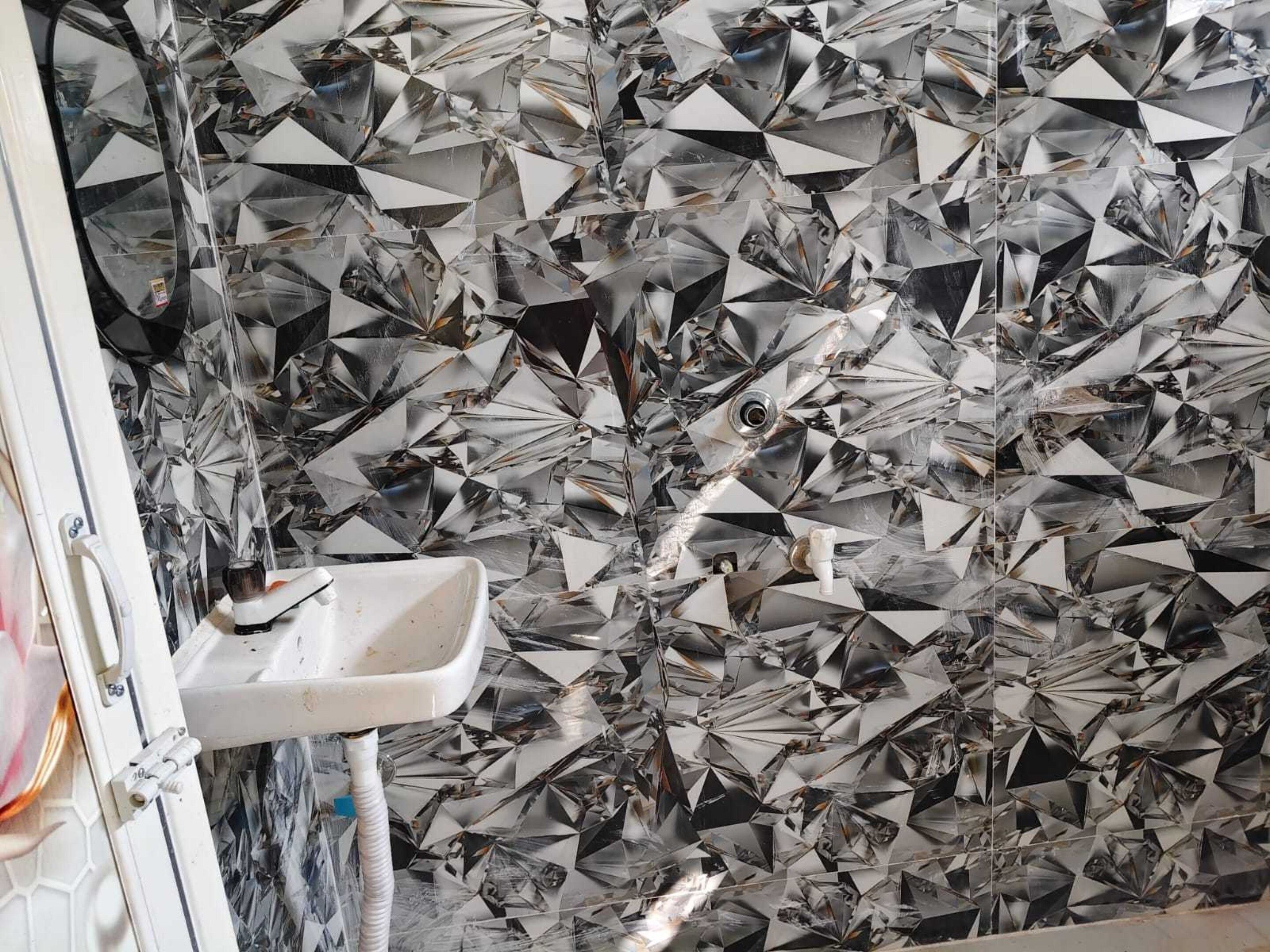 Une salle de bain avec un lavabo et un mur recouvert de carreaux géométriques réfléchissants.