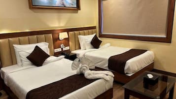Une chambre d’hôtel avec deux lits, une table de chevet, un téléviseur fixé au mur et une fenêtre donnant sur un paysage agréable.