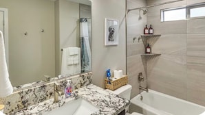 Ein modernes Badezimmer mit Marmorwaschbecken, einem großen Spiegel, einer Dusche und einer Toilette.