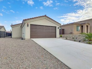 A residential garage with a brown garage door, a concrete driveway, and a gravel area. -  Havasu Palisades - Lake Days & Sunset Nights- Modern  Retreat - Sleeps Seven (Lake Havasu City)