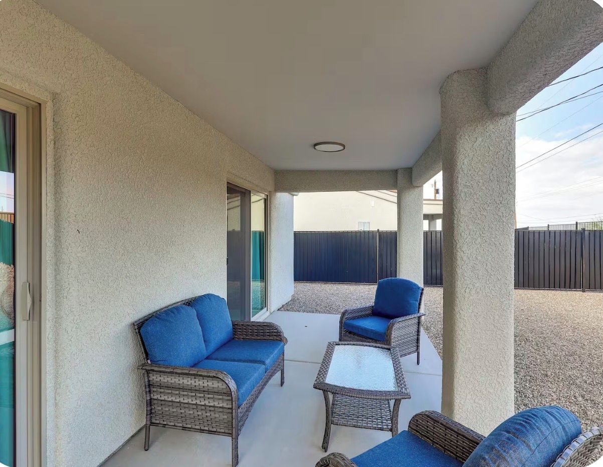 Eine überdachte Terrasse mit Korbmöbeln und einer Glastür, die zu einem Außenbereich führt.