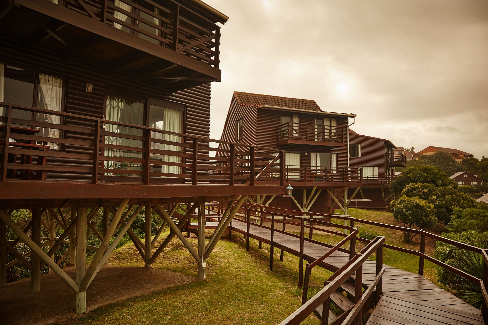 A wooden structure with multiple levels, including a deck and balconies, surrounded by greenery.