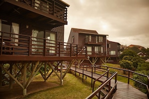 A wooden cabin with a balcony and a deck. - Kowie River Chalets (Port Alfred)