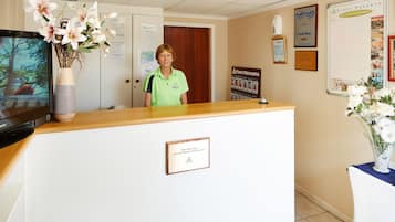 A reception desk with a sign that reads 'Don't Miss Out! Join Our Weekly Get Together!' in a hotel lobby.