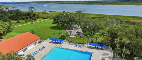 A swimming pool with lounge chairs and a view of a lake.
