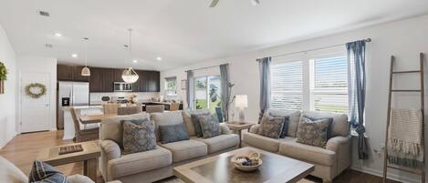A modern living room with a sofa set, a coffee table, and a ceiling fan.