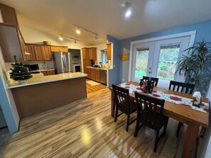 A modern kitchen with wooden cabinets, a central island, and a dining area with a table and chairs.