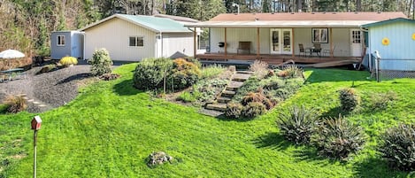 Ein Wohnhaus mit gepflegtem Rasen, einer Terrasse und Gartenmöbeln sowie einem kleinen Schuppen.