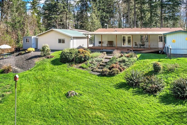 A residential property with a well-maintained lawn, a patio area with outdoor furniture, and a small shed.