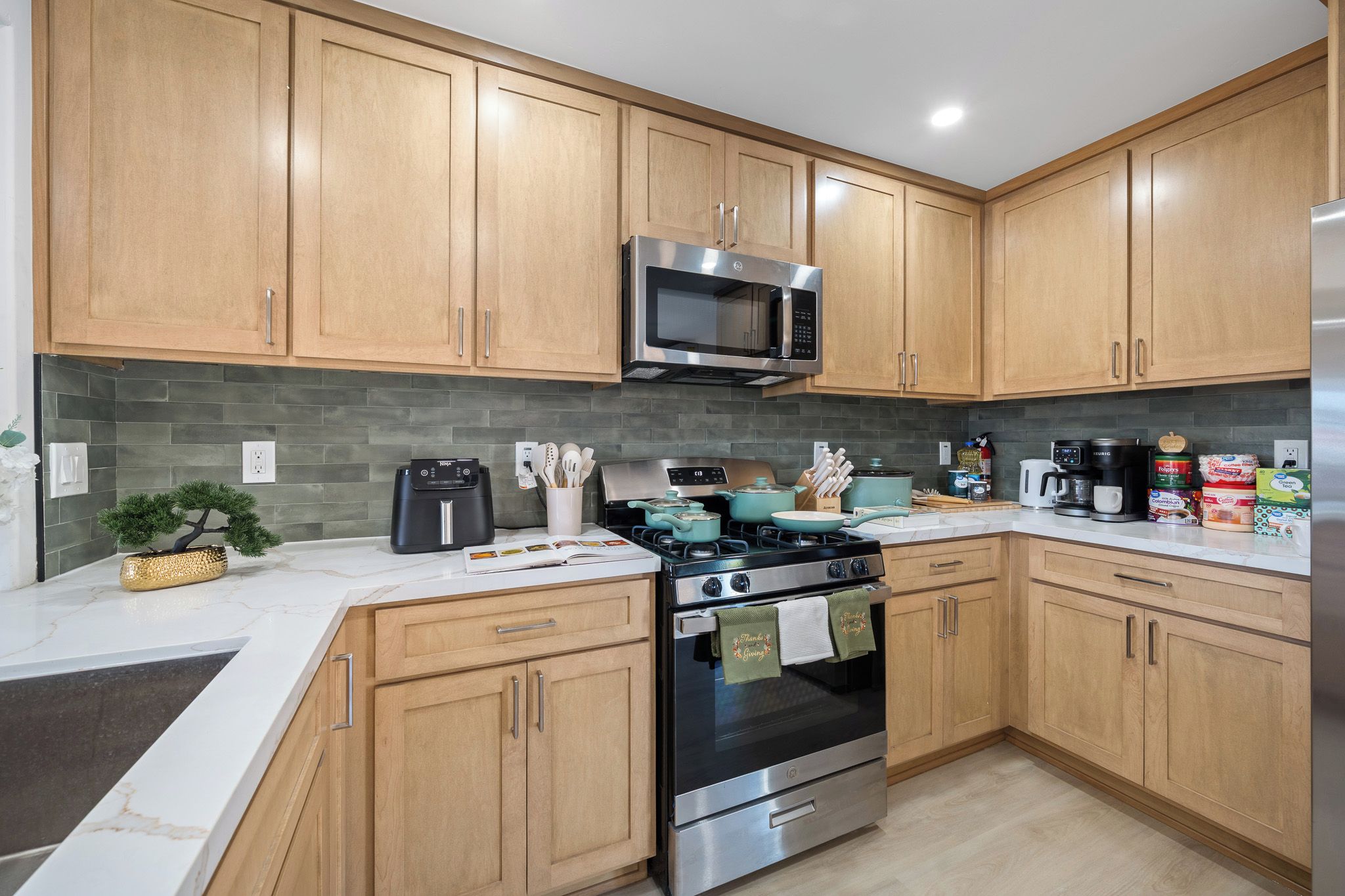 A modern kitchen with wooden cabinets, a stainless steel range, a microwave, and a stove.