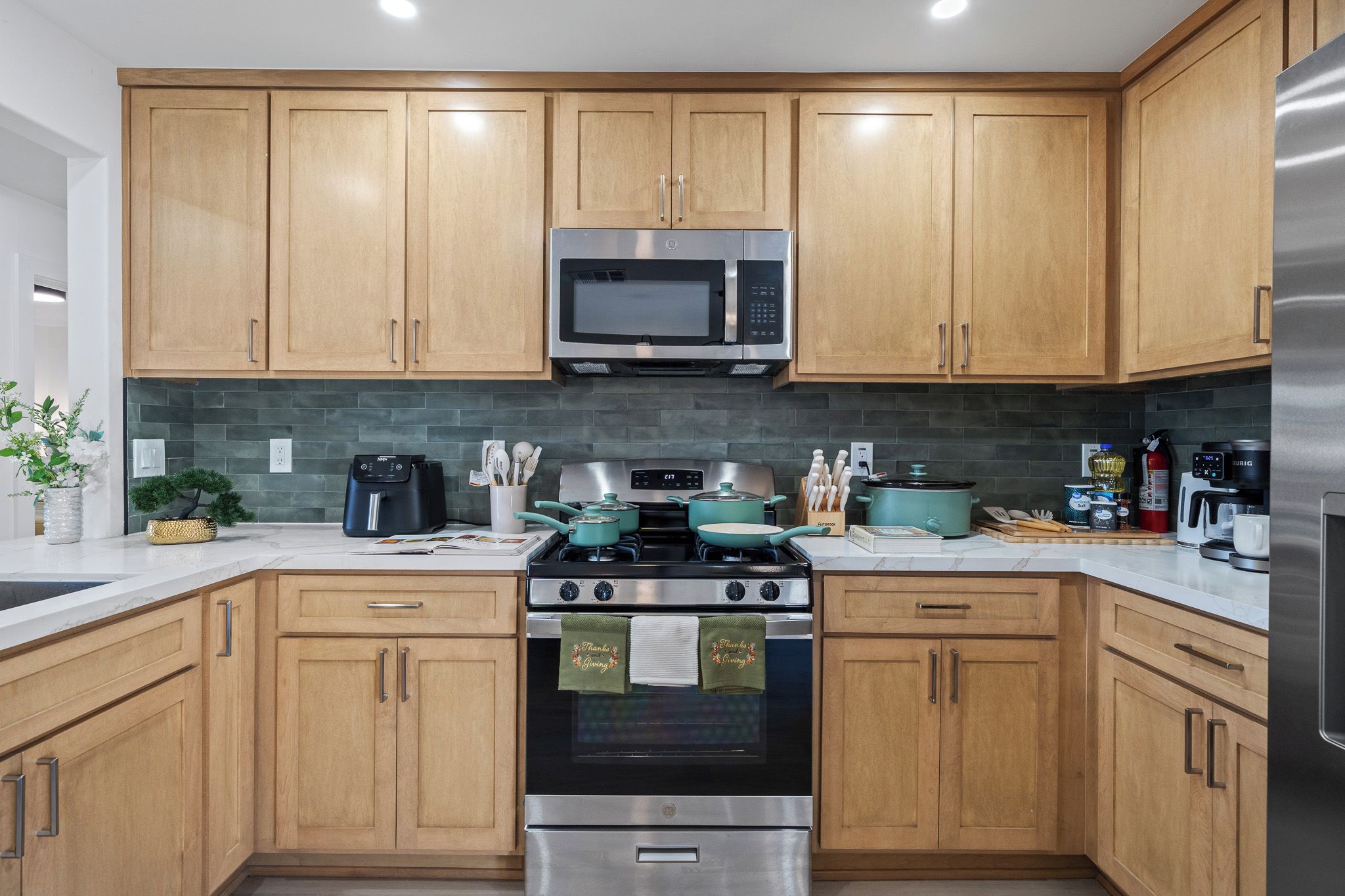Una cocina moderna con armarios de madera, una estufa de acero inoxidable, un microondas y diversos electrodomésticos.