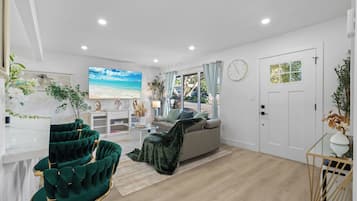 A modern living room with a sofa, a TV, and a dining area with a table and chairs.