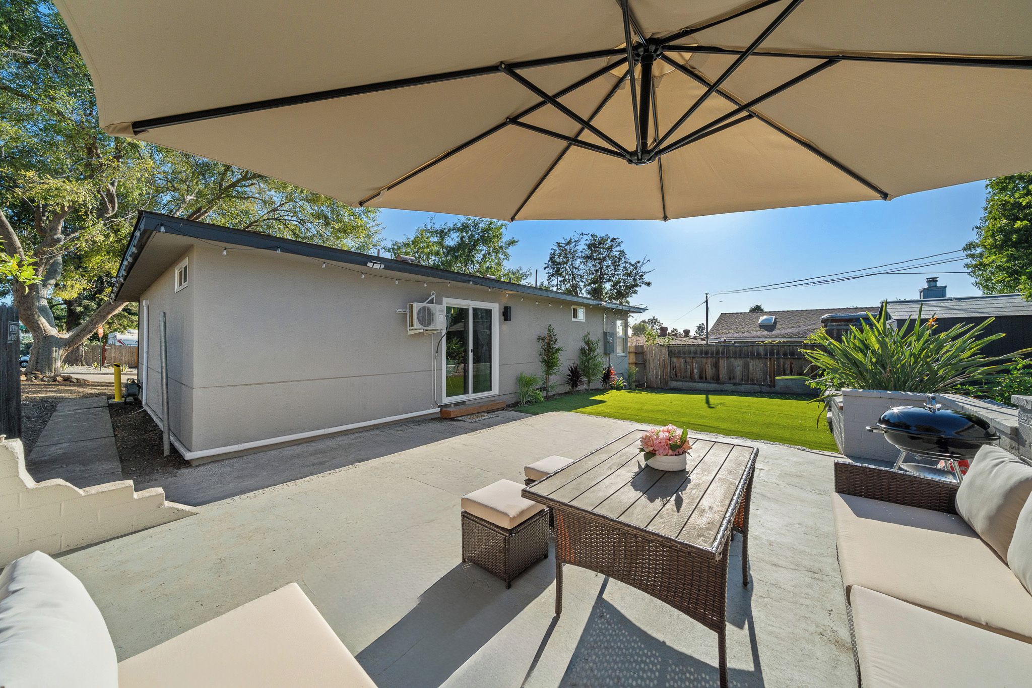A patio area with outdoor furniture, a covered seating area, and a small building with a sliding door.