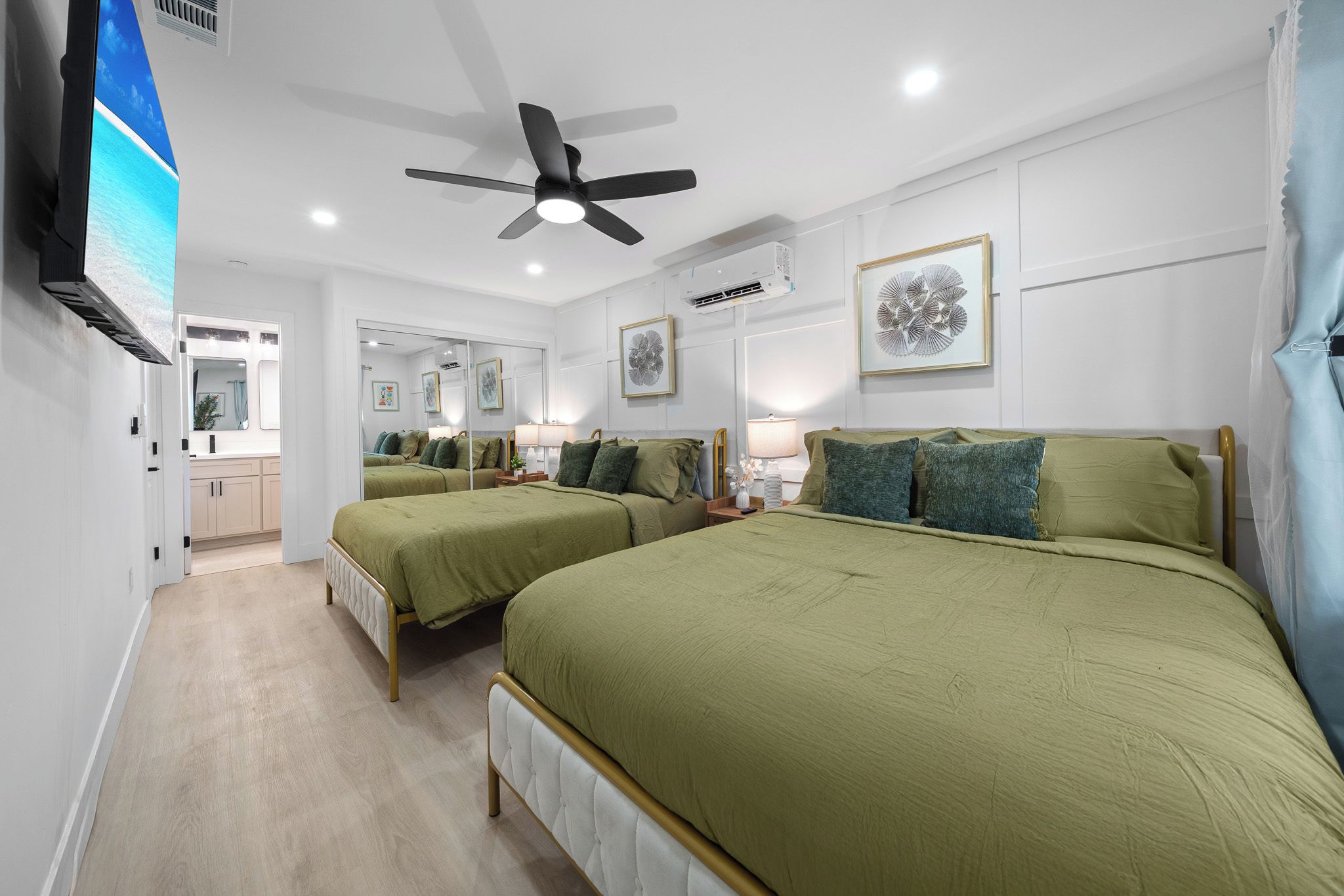 A hotel room with a large bed, a ceiling fan, a flat-screen TV, and a bathroom visible through an open door.