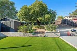 A residential property with a well-maintained lawn, a large tree, a wooden fence, and a garage. - Gated Yard, King Bed, Parking, Ranch-Style La Mesa (La Mesa)
