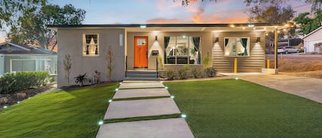 A modern two-story house with a well-maintained lawn and a pathway leading to the front door.
