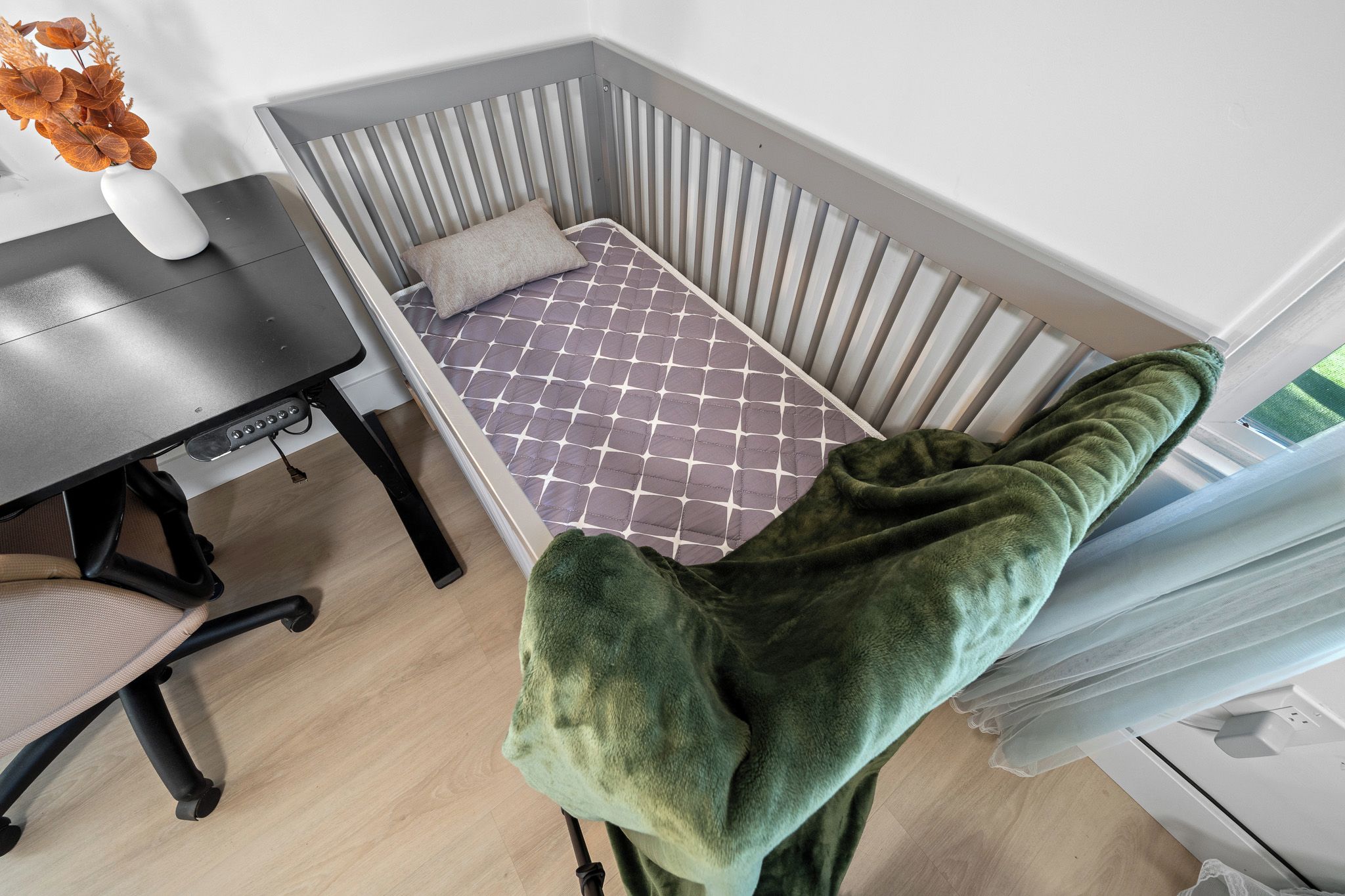 Habitación de esquina con cama, mesa y silla.