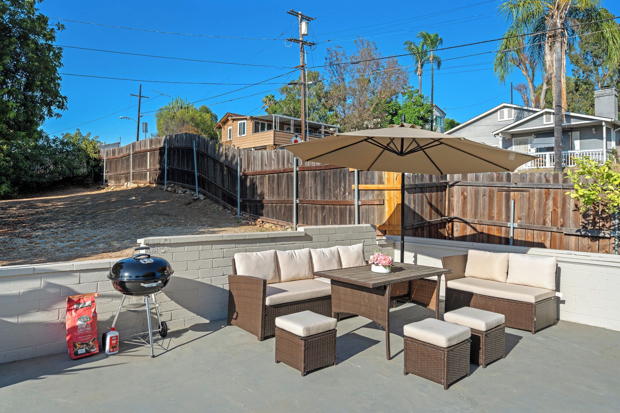 An outdoor patio with wicker furniture, a barbecue grill, and a covered umbrella.
