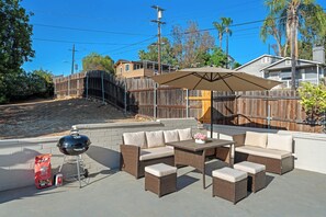 An outdoor patio with wicker furniture, a barbecue grill, and a covered umbrella. - Gated Yard, King Bed, Parking, Ranch-Style La Mesa (La Mesa)