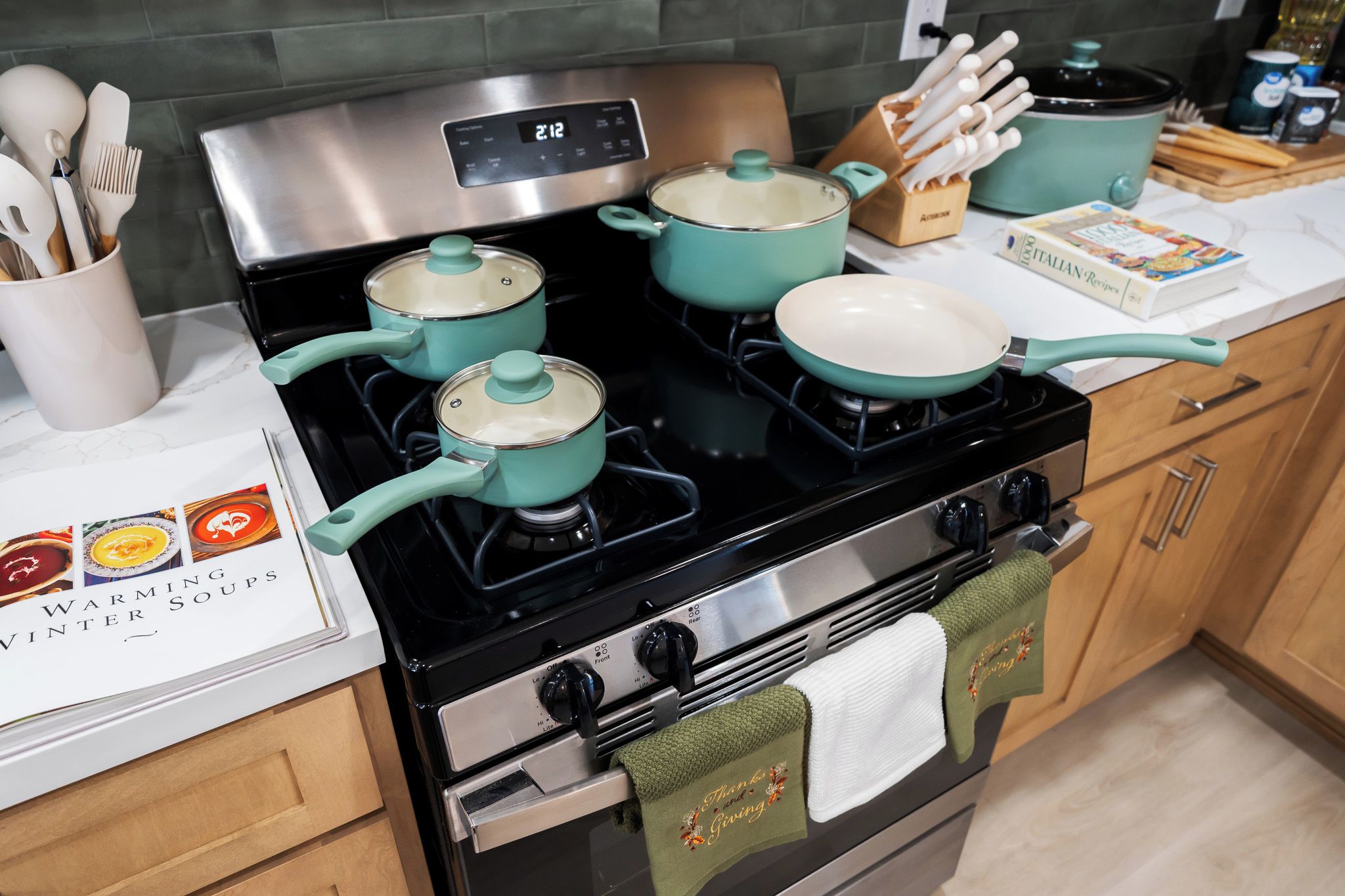 Una cocina con estufa, ollas y un libro de cocina titulado 'WARMING VINTER SOUPS'.