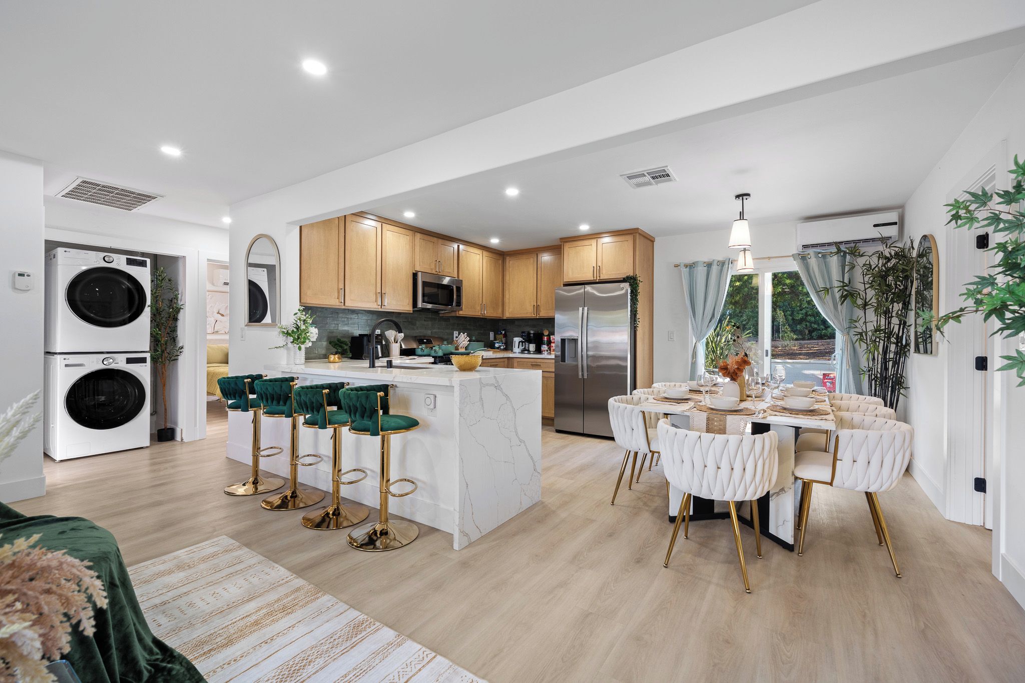 A modern kitchen with a central island, bar stools, and a dining area with a white table and chairs.