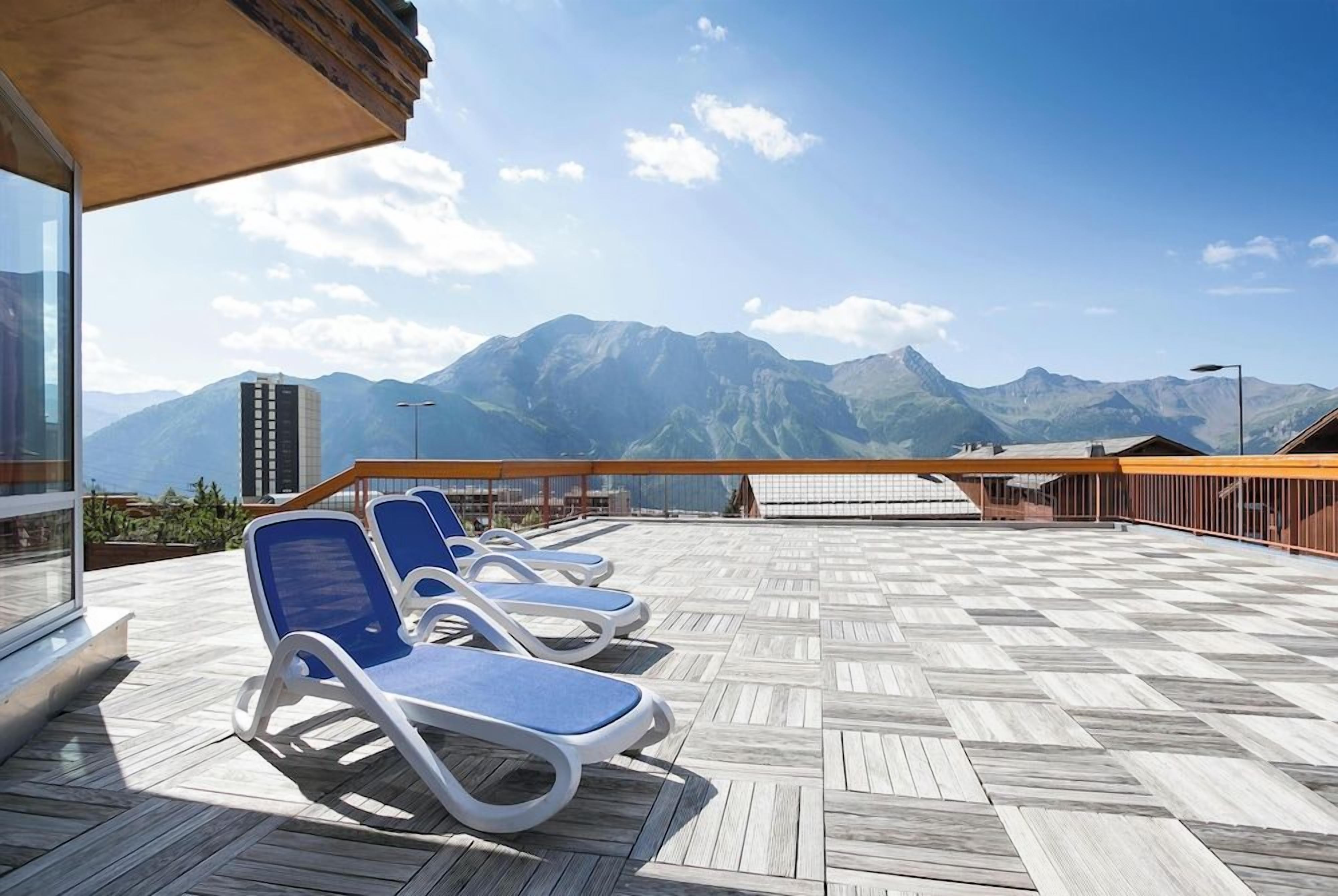 A deck with lounge chairs and a view of mountains.