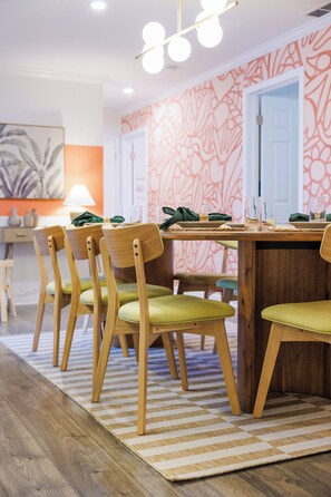 A dining area with a wooden table, green upholstered chairs, and a patterned rug. - Sapphire Haven - Family Amenities+Central Location (Largo)