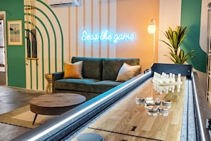 A bowling alley with a neon sign, a green-striped wall, and a sofa with cushions. - Sapphire Haven - Family Amenities+Central Location (Largo)