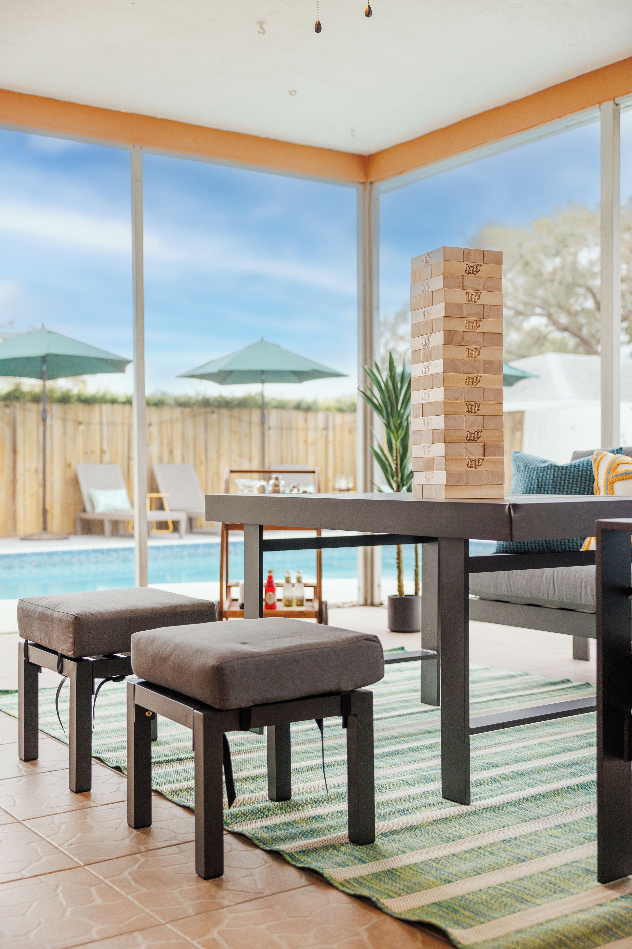 A patio area with a pool, outdoor furniture, and a wooden game table.