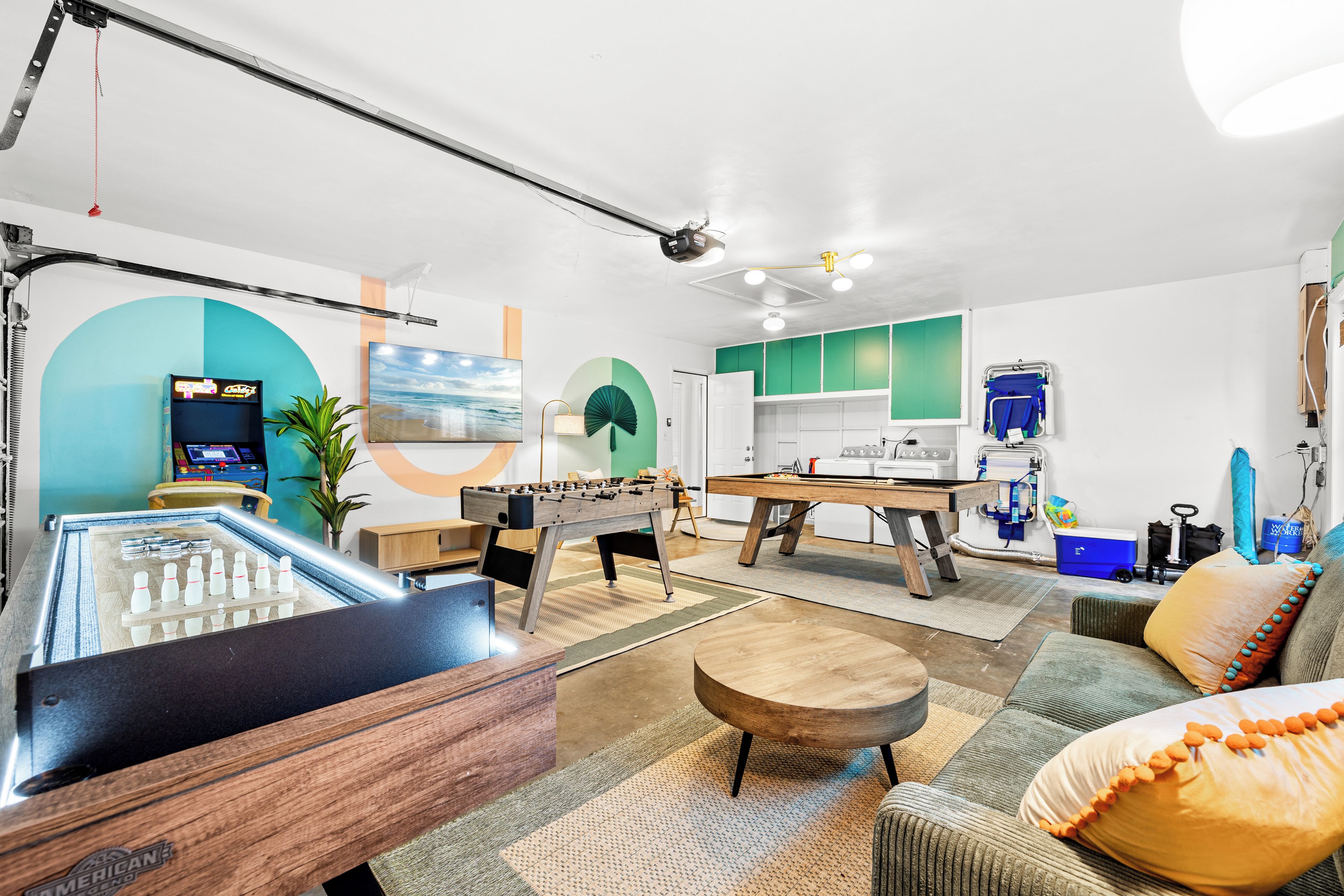 Een moderne woonkamer met een tafelvoetbaltafel, een pooltafel en een gezellige zithoek met een bank en fauteuils.