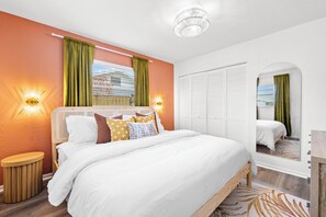 A bedroom with a bed, bedside lamps, a round wooden nightstand, a mirror, and a wardrobe. - Sapphire Haven - Family Amenities+Central Location (Largo)