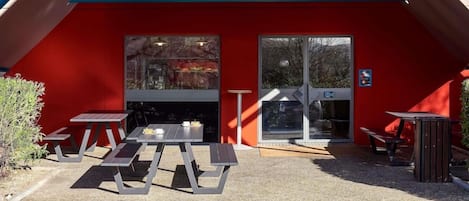 A hotel entrance with a red facade, outdoor seating, and a sign reading 'hotelF1.com'.