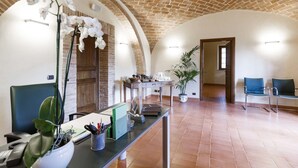 A spacious room with a high arched ceiling, a reception desk, a potted plant, and a seating area. - Tenuta di Montecucco - Collemassari Hospitality (Cinigiano)
