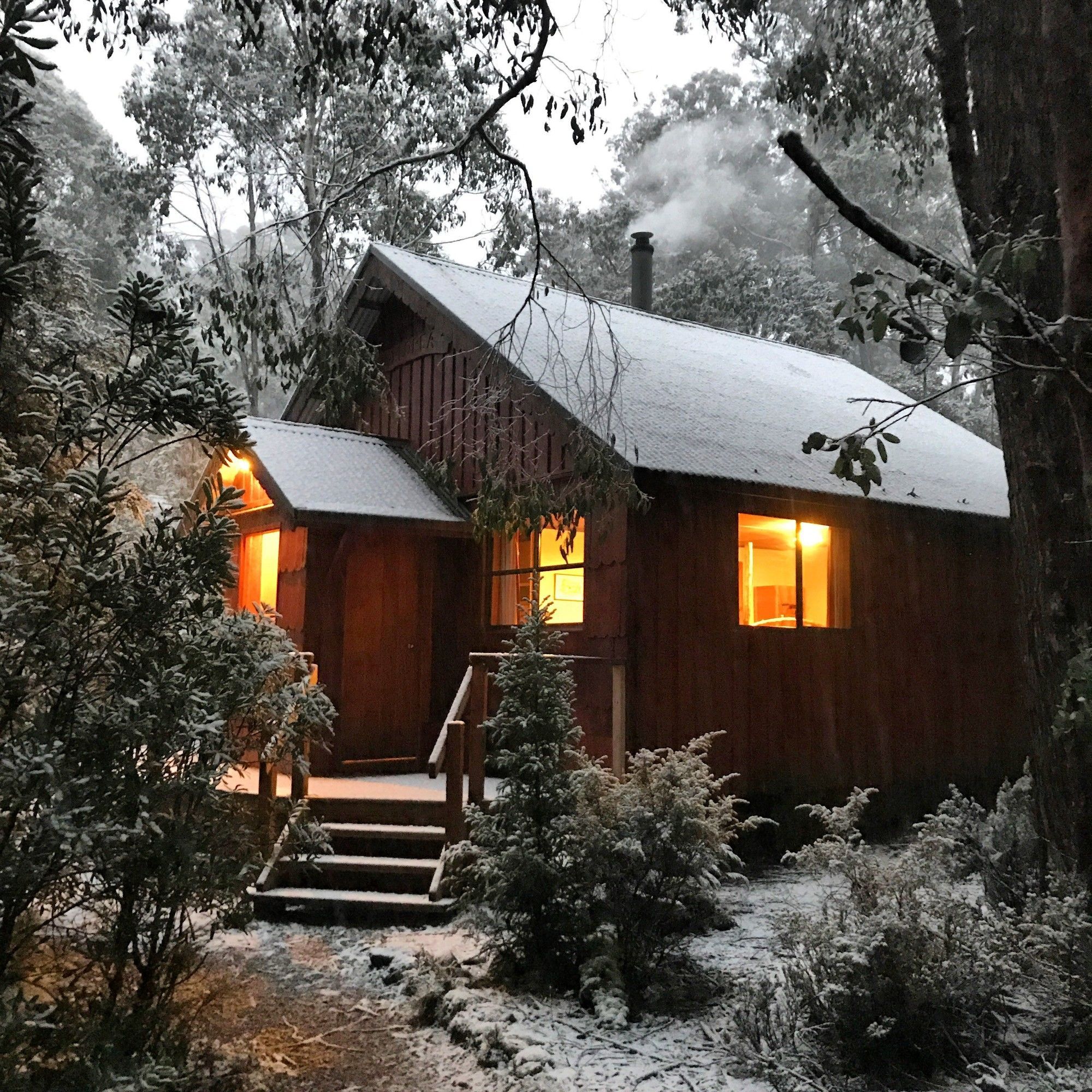 A wooden cabin with a sloped roof, a front porch, and a staircase leading to the entrance.