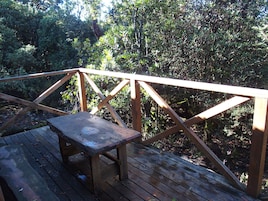 Una terraza de madera con una mesa metálica y una barandilla.