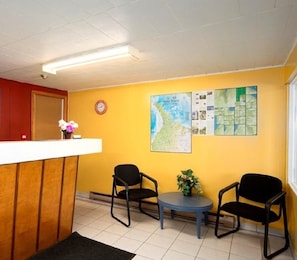 A reception area with a reception desk, two chairs, a small table, and a wall with a map and informational posters. - Save Inn Kincardine (Kincardine)