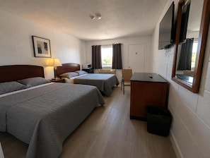 A hotel room with two beds, a desk, a chair, a TV, and a window with curtains. - Save Inn Kincardine (Kincardine)