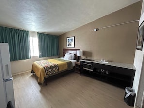 A hotel room with a bed, a desk, a sink, and a window with curtains. - Traveler Inn Sterling (Sterling)