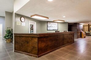A reception desk with a clock, framed picture, and a small plant. - Traveler Inn Sterling (Sterling)