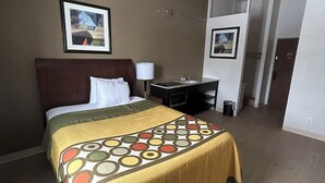 Habitación de hotel con cama, escritorio y silla. Se ve una puerta que da a otra habitación.