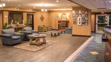 A hotel lobby with a reception desk, seating area, and a wall with framed pictures.