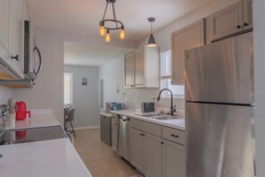A modern kitchen with stainless steel appliances, a white countertop, and a pendant light fixture. - Chic 4-bed with AC in beautiful Colorado Springs near downtown and pet friendly (Colorado Springs)