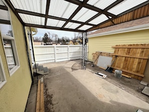 A covered outdoor area with a concrete floor, wooden fence, and construction materials. - Chic 4-bed with AC in beautiful Colorado Springs near downtown and pet friendly (Colorado Springs)
